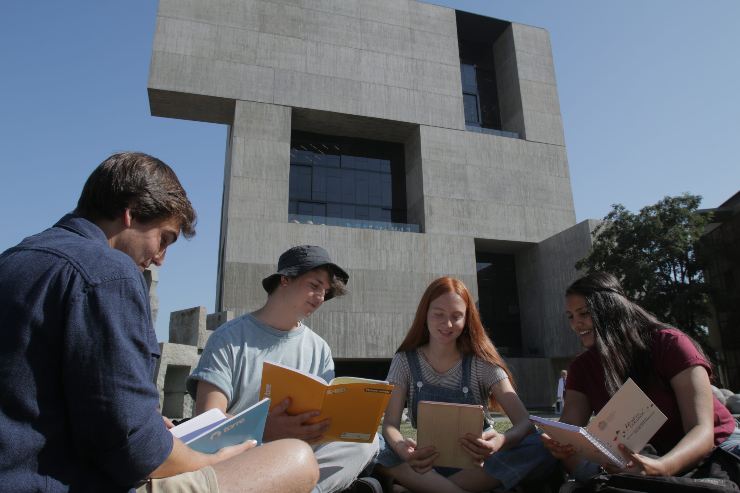 Estudiantes sentados frente al centro de Innovación mientras leen.