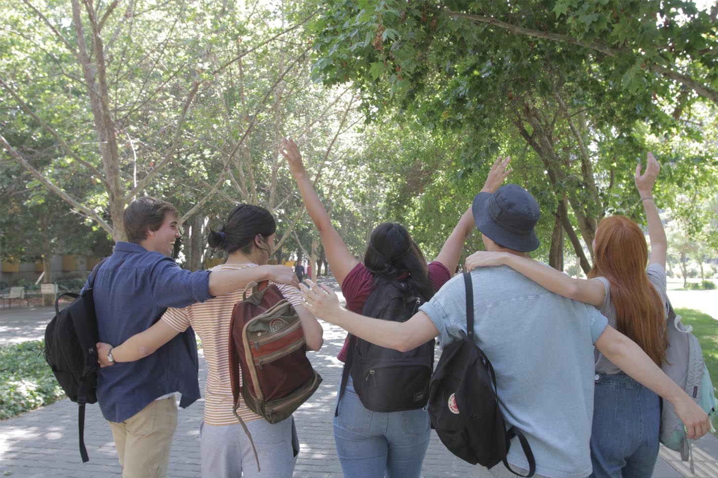 Estudiantes con mochilas paseando felices por el campus San Joaquín.