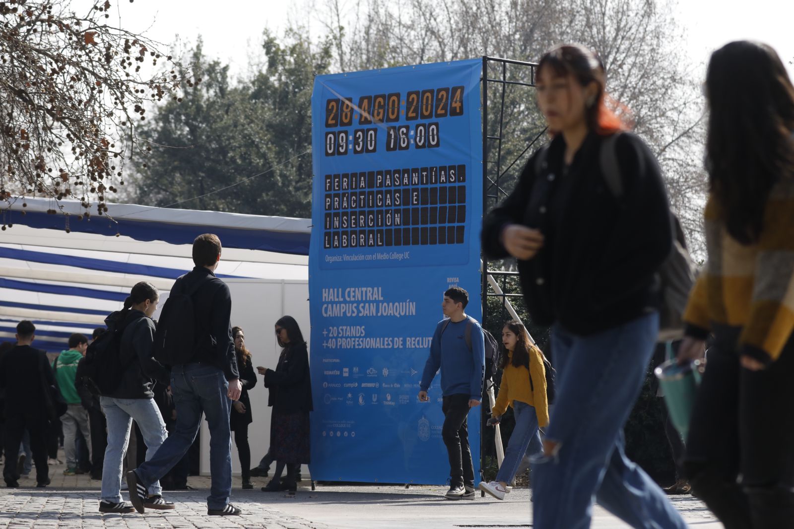 Gigantografía de afiche Feria de Pasantías, Prácticas e Inserción Laboral de College en medio del patio con personas caminando