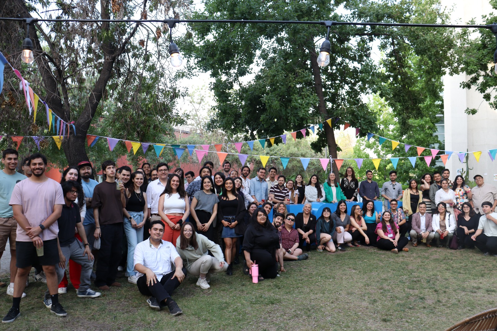 Gran grupo de personas sonriendo a la cámara acompañados de las letras College UC